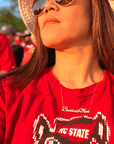 A life style product picture of Baseball Mom necklace. A model is wearing a Baseball Mom necklace at a baseball game. Side View