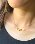 A closeup picture of a MOM baseball necklace in gold