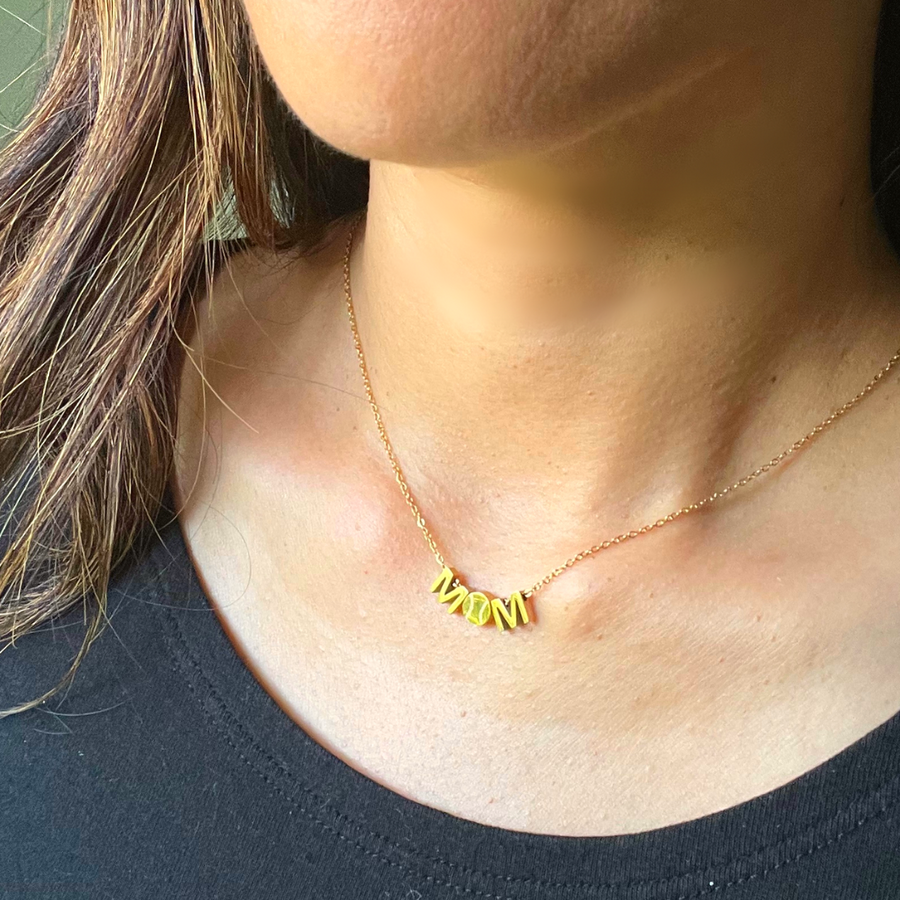 A closeup picture of a MOM baseball necklace in gold