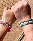 custom baseball/softball heishi bead bracelets in lifestyle picture in pink and teal